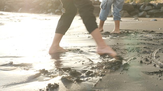 Couple moving feet in the wet sand