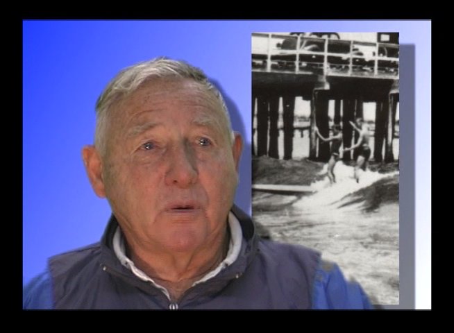 An elderly man shares personal recollections while historical black-and-white archival footage displays on an adjacent screen. The segment highlights individual narrative reflections paired with visual cultural documentation.