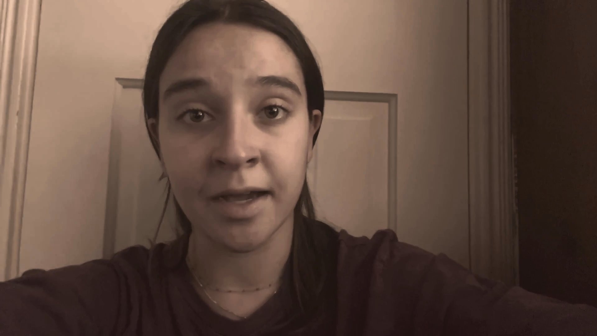 A young woman speaks directly to the camera, sharing a narrative with varied emotional expressions. Her delivery remains focused and articulate against a plain interior background.