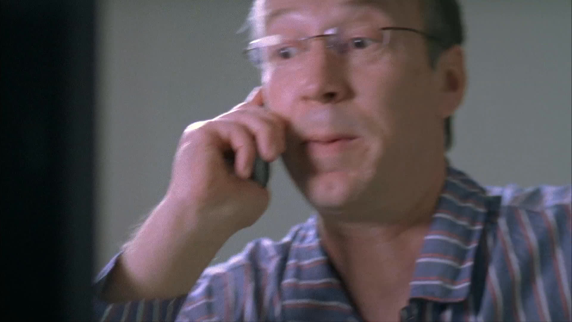 A man engages in an animated phone conversation while walking down an urban sidewalk, intercut with scenes of a performance rehearsal involving actors in canine costumes.