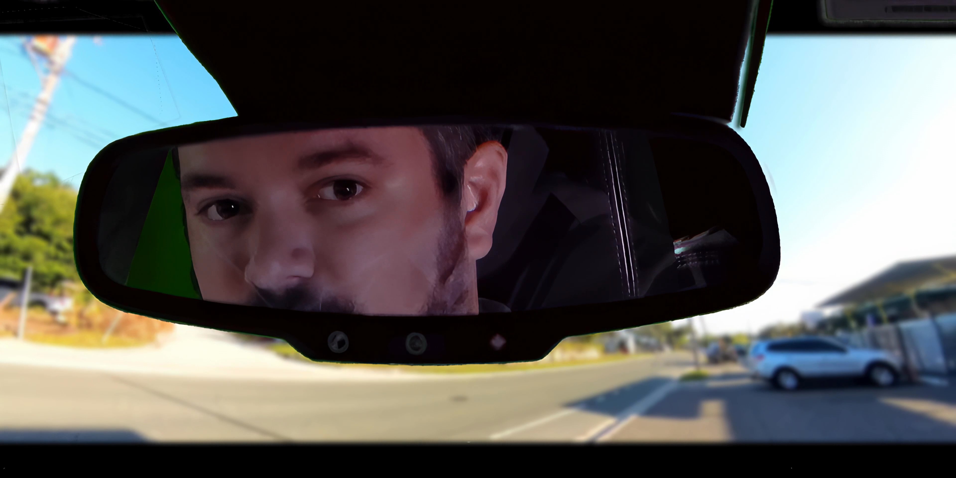 Two men engage in a tense conversation while riding as passengers in a moving vehicle. The interaction oscillates between calm observation and heated verbal exchange.
