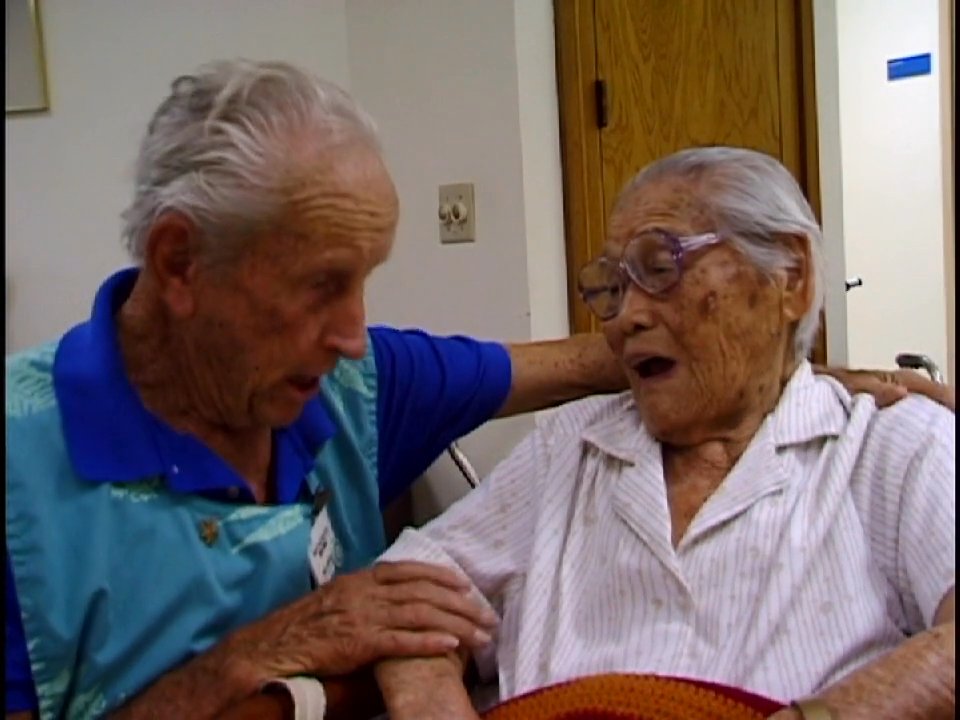 A nurse engages with elderly residents in an assisted living environment, fostering social connection and providing compassionate care. The interaction highlights the importance of emotional support within a clinical setting.