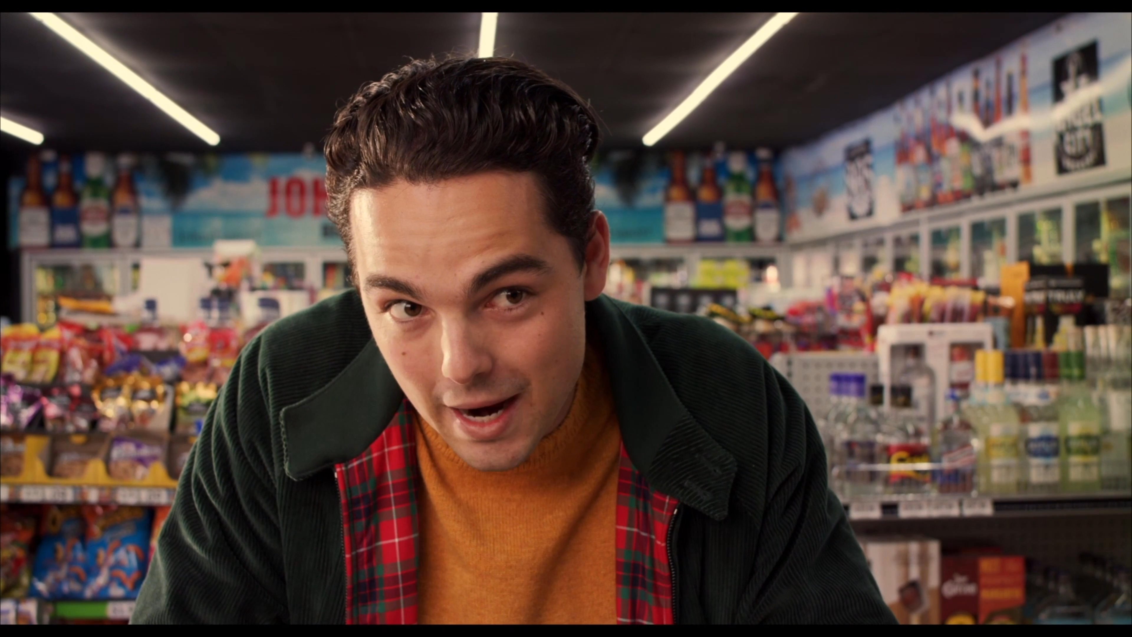 A liquor store clerk engages with a customer, resulting in the placement of a bottle of Scorpion Tequila on the lottery ticket counter.