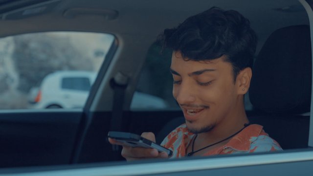 A teenage boy sitting in a car and smiling