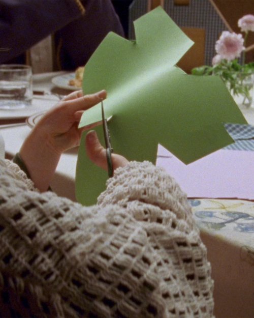 Close-up of hands cutting green paper with scissors, framed as a vertical social video still
