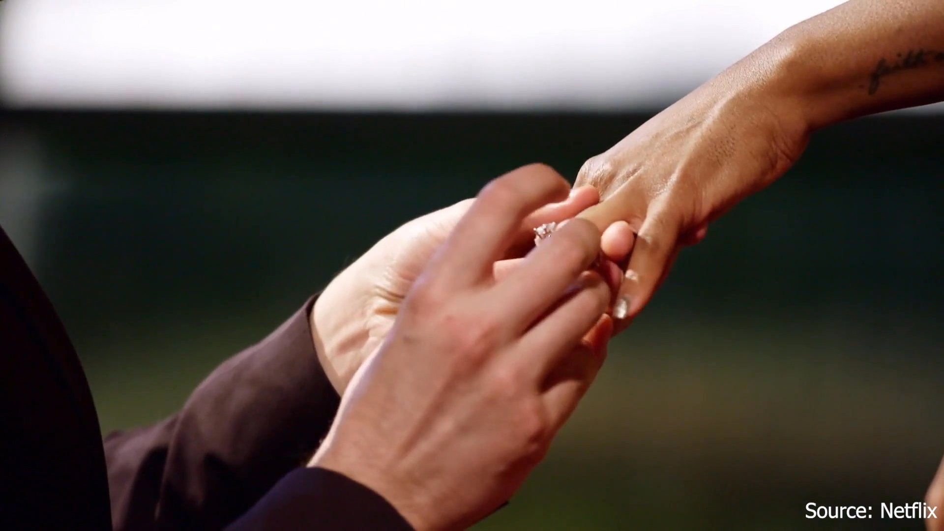 A man kneels to propose marriage to his partner in a formal setting, followed by an emotional exchange between the couple as they celebrate their new commitment.