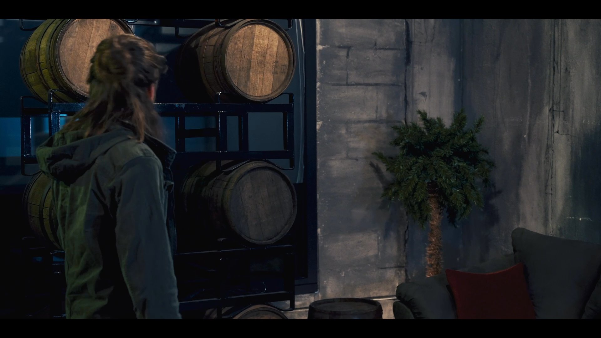 Two individuals engage in a professional discussion within a lounge environment featuring industrial barrel decor, followed by a woman examining a glass item at a bar counter.
