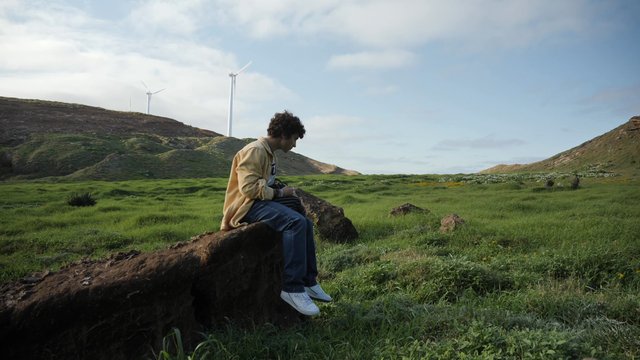 A man sitting on a rock in a field