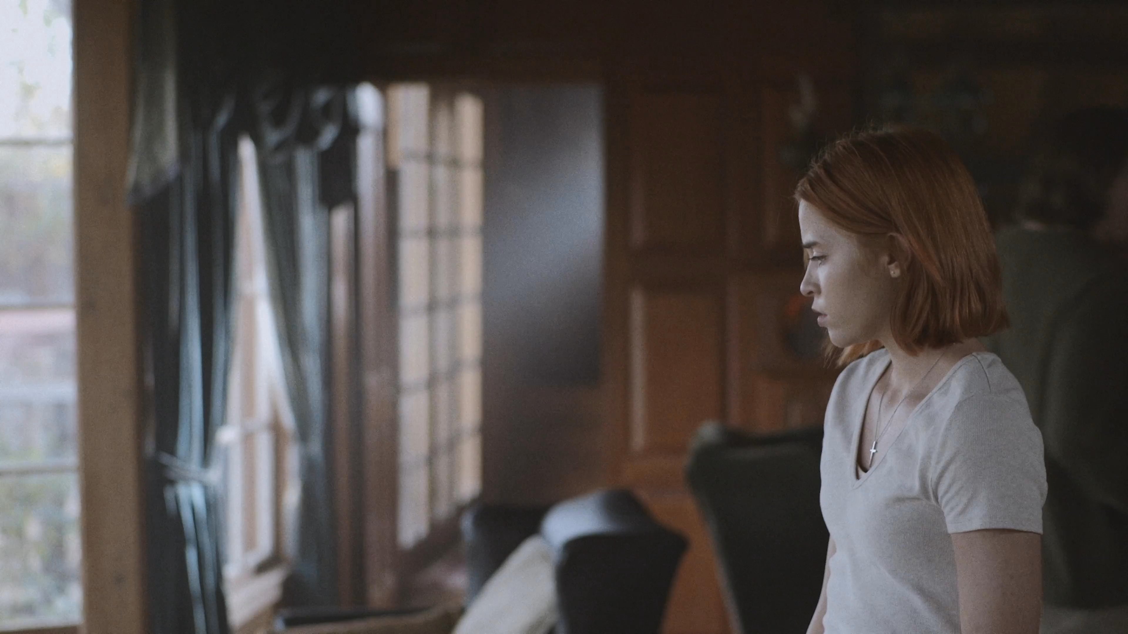 A tense encounter occurs between two individuals in a wood-paneled interior, where one person departs after a brief moment of interaction. The scene shifts to focus on the remaining individual who appears contemplative while gazing out a window.