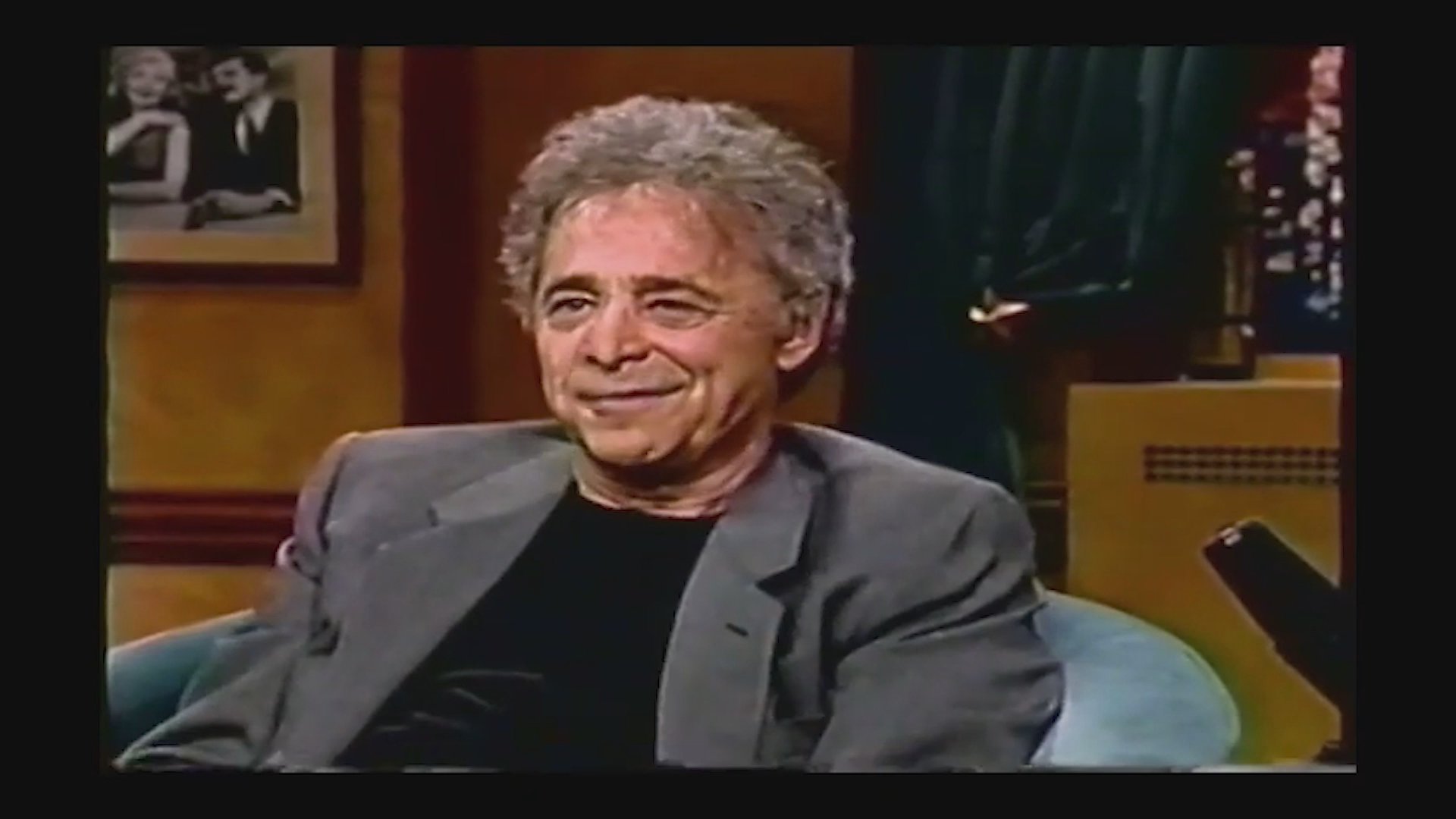 Producer Norman Lear shares stories and laughs while seated as a guest on a late-night talk show set.