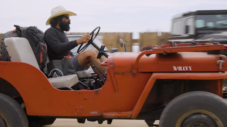 Man driving vintage Jeep in parking lot of Pioneertown Motel