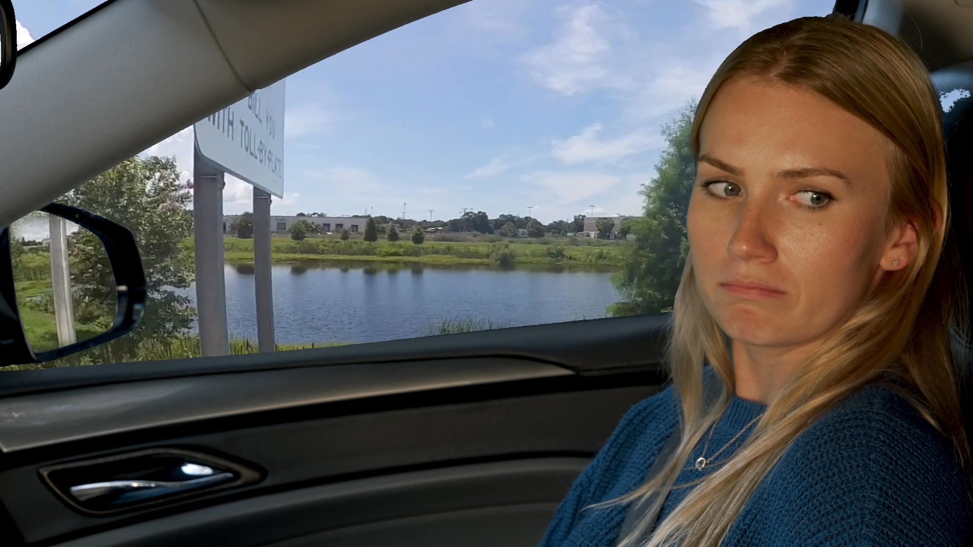 A man and a woman engage in conversation while traveling together in a moving vehicle. The scene captures their interaction as they drive along a highway during daylight hours.