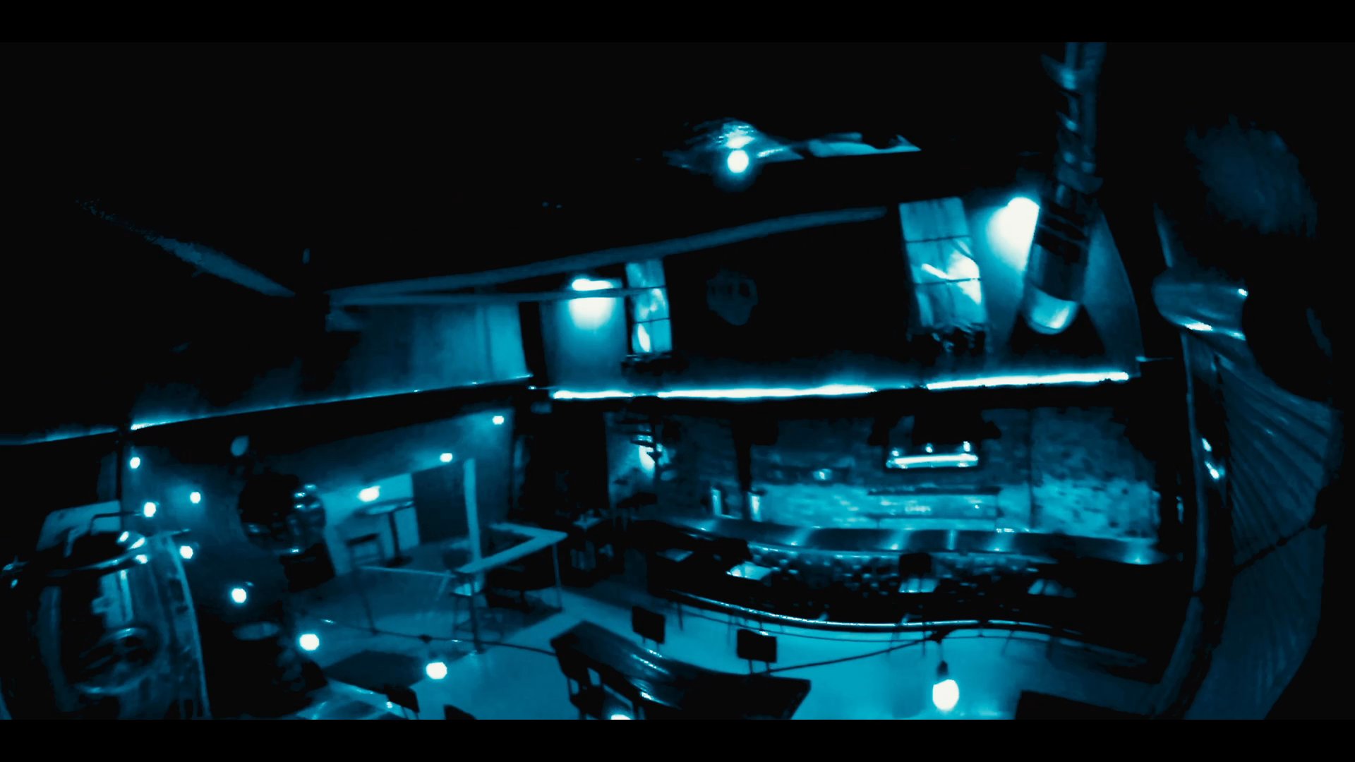 A group of individuals relaxes in a dimly lit brewery lounge before the scene shifts to the establishment's exterior at night.