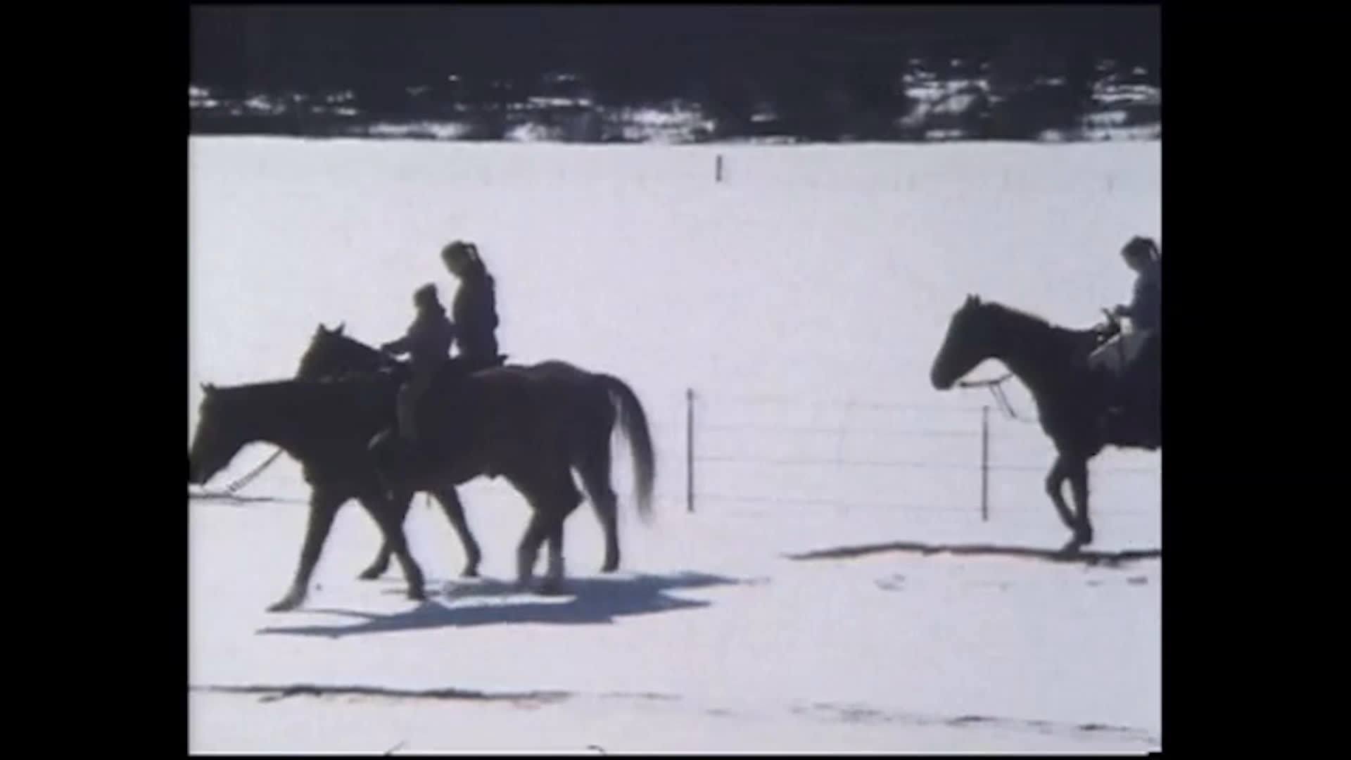 A woman embraces a child outdoors before several riders cross a broad snow-covered field on horseback. They discuss a toe that hurt after being stepped on, and the child says it no longer hurts.