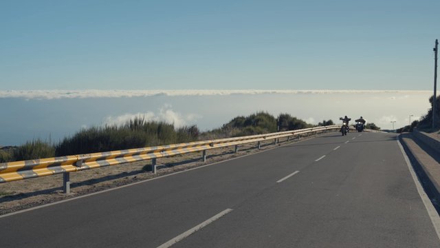 Two bikers driving down a straight road
