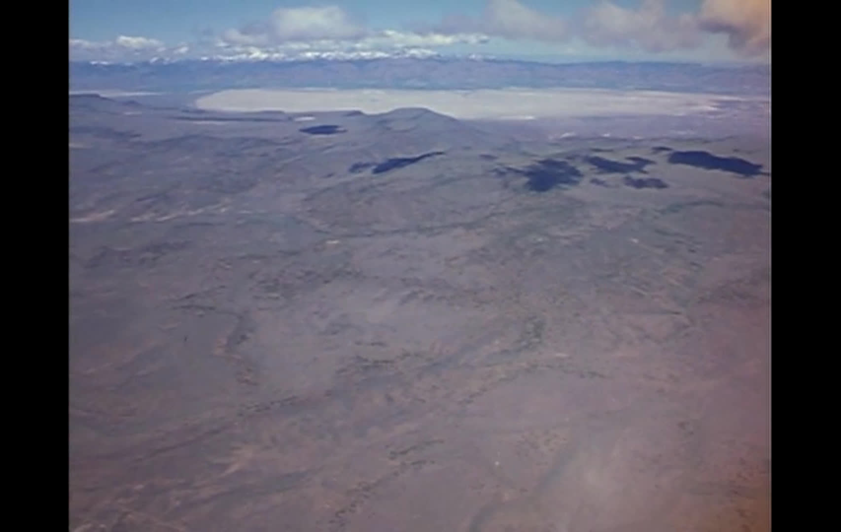 Aerial views sweep across vast, dry western ranges, distant mountains, and a green valley as birds cross the open sky. Narration describes ranchers’ reliance on federally managed summer pasture and private lands surrounded by public range.