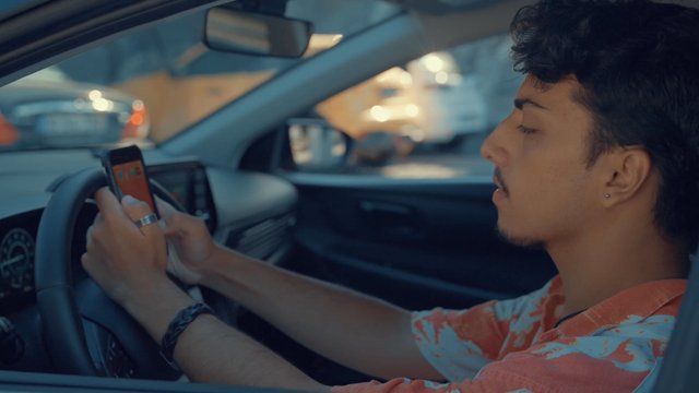 A teenager messaging on his phone while sitting in his car