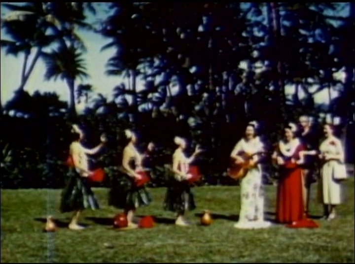 The footage opens with views of Waikiki Beach and the iconic Royal Hawaiian Hotel before transitioning to a traditional hula dance performance in a tropical outdoor setting.