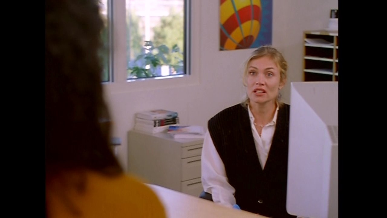 Two colleagues engage in a professional conversation within an office setting, alternating focus between their computer work and their dialogue.