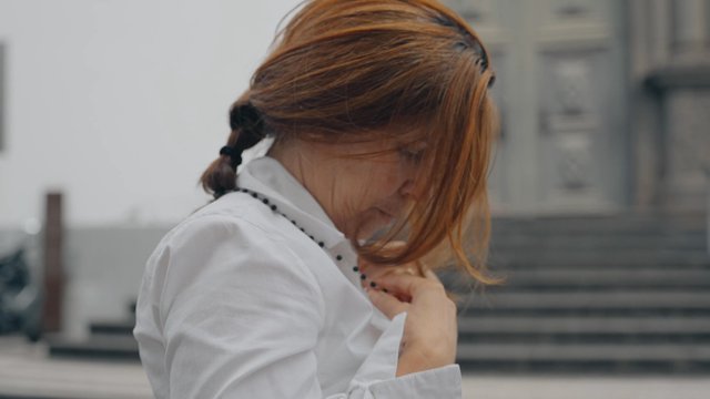 A woman puts rosary beads around her neck