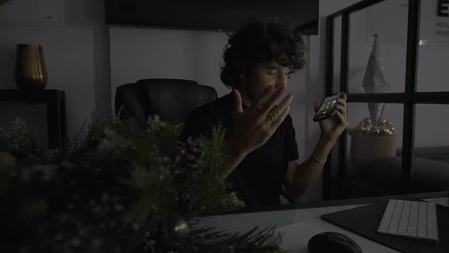 A man sitting at his desk and talking on his mobile phone