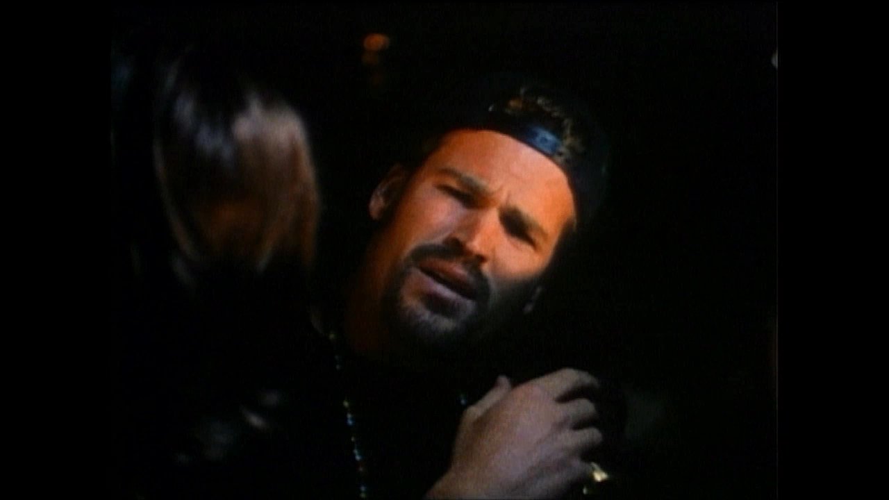A man and woman engage in a deeply emotional and focused conversation, utilizing expressive hand gestures and intense facial expressions within a dimly lit environment.