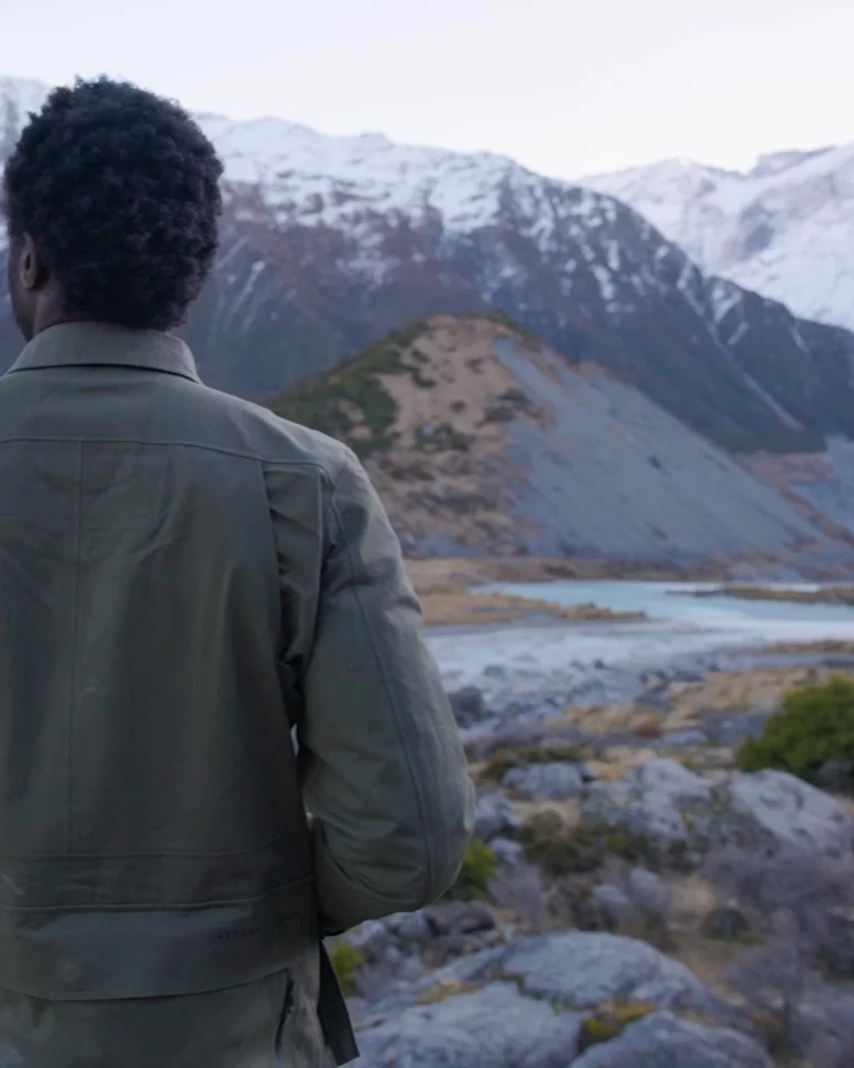 Man turning and holding a Leica camera in New Zealand landscape