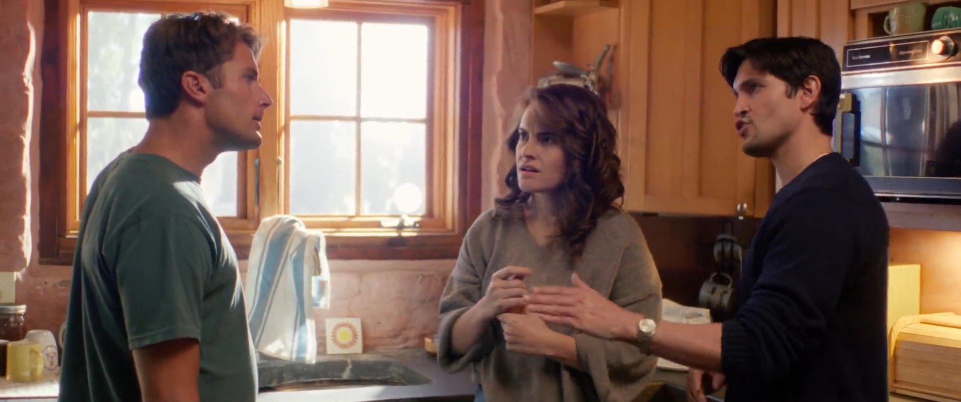 A man and woman engage in a serious, tense discussion within a kitchen setting, reflecting personal conflict and interpersonal disagreement.