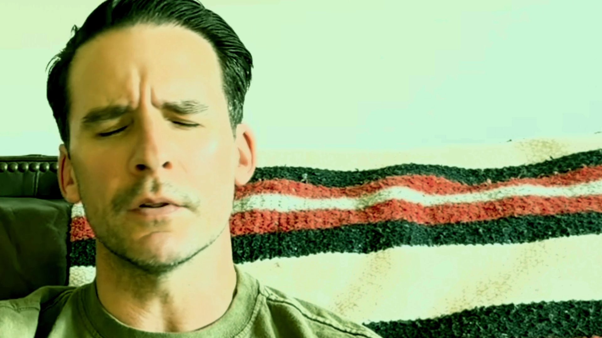 A man engages in a direct, conversational monologue while seated, exhibiting varying facial expressions and vocal focus.