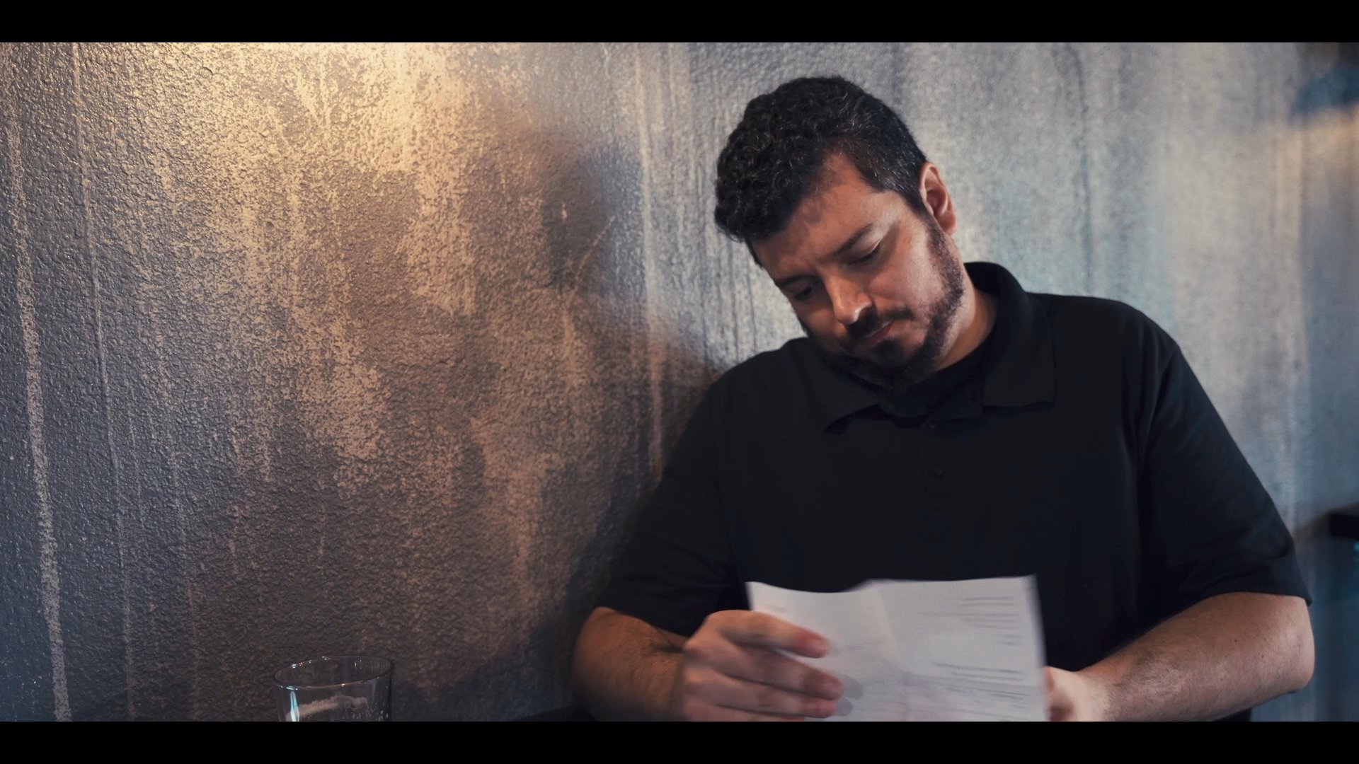 A man passes a document to his colleague who proceeds to carefully review and read the contents.