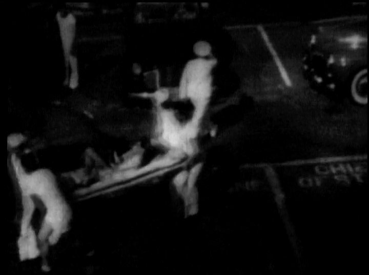 Explosions and smoke rise over the Pearl Harbor naval base during an attack as medical personnel evacuate wounded sailors. The sequence concludes with survivors aboard a small boat amidst the aftermath of the conflict.