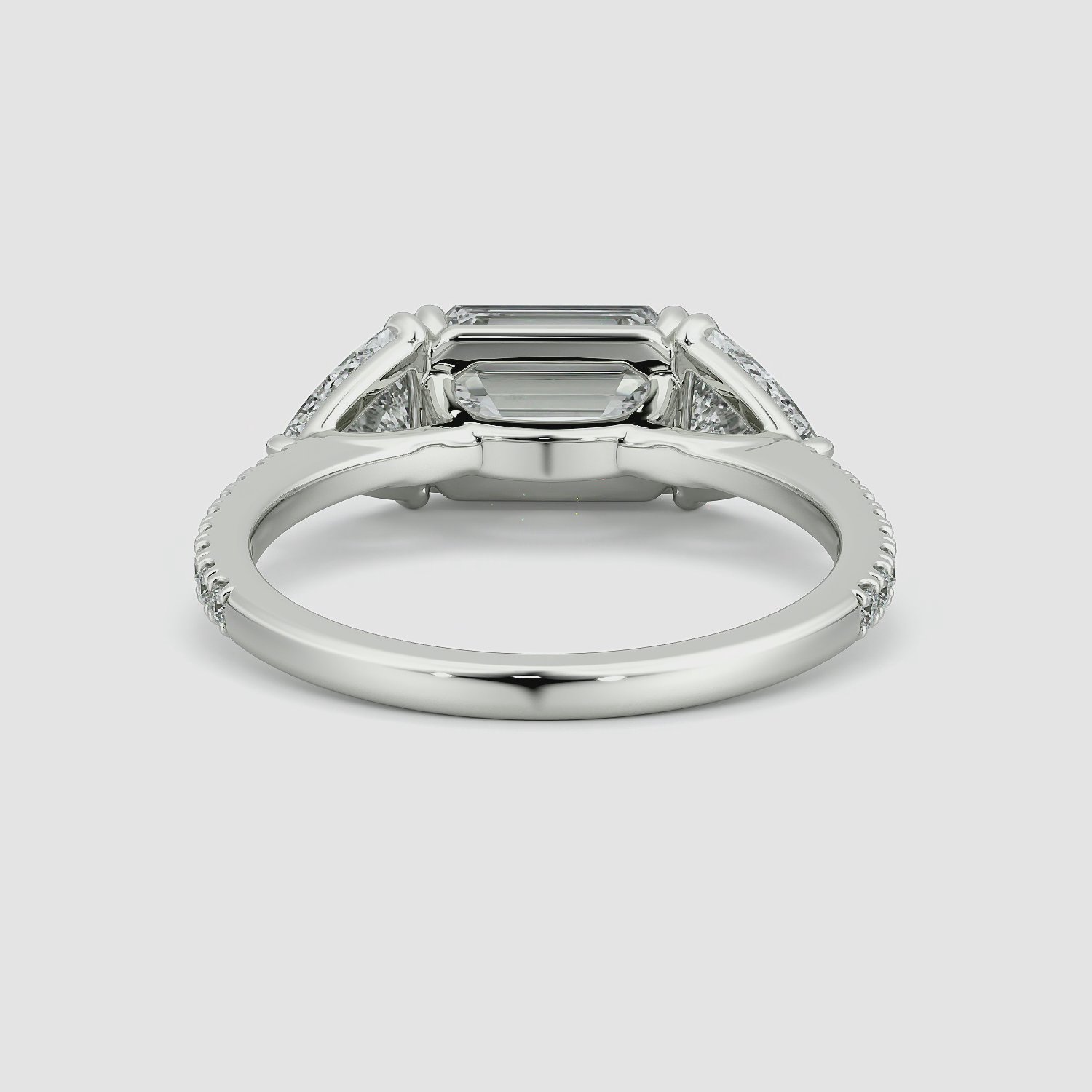 The Three Stone | Emerald | Platinum | bandAccent: Pavé | diamondOrientation: horizontal | sideStoneCarat: 0.50ct | sideStoneShape: Trillion | caratWeight: other
