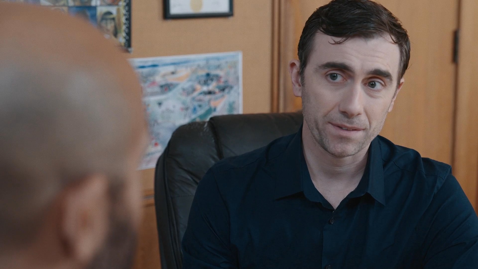 Two professionals engage in a focused, collaborative discussion while seated at an office conference table. The interaction centers on a professional exchange of ideas to facilitate business strategy.