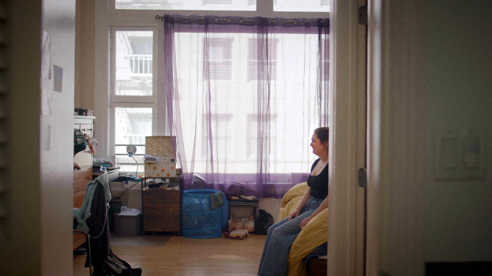 A man attempts to comfort a woman during a tense interaction in a bedroom, leading her to withdraw into the bathroom to compose herself in private.