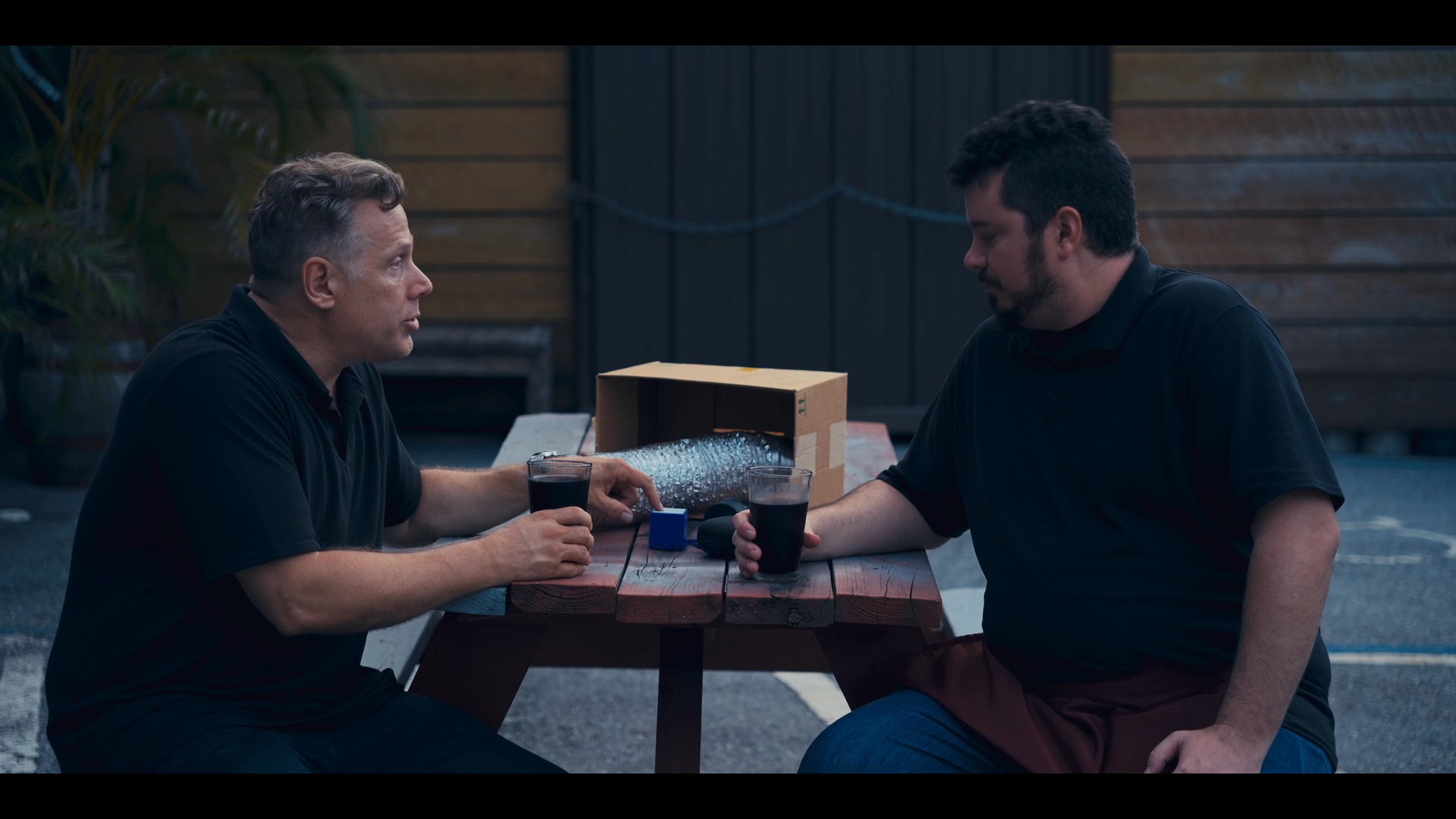 Brewery staff engage in a professional discussion within an industrial workspace, transitioning to an outdoor evaluation of craft beverages. The sequence captures a collaborative atmosphere focused on product quality and operational dialogue.