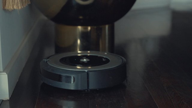 Person pressing the ‘clean’ button on a robot vacuum cleaner
