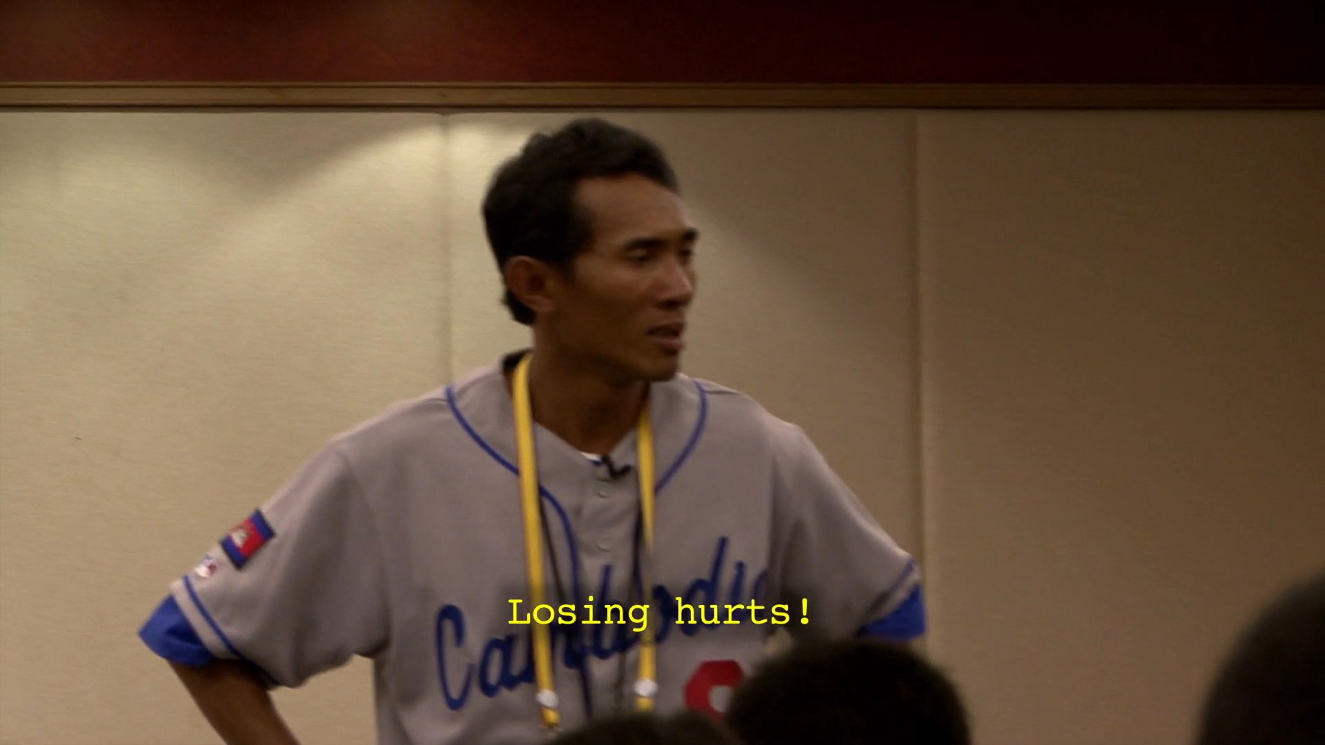 A frustrated coach addresses his team in a meeting, expressing deep disappointment and questioning their commitment following a loss. The players listen silently while the coach emphasizes the pain of losing.