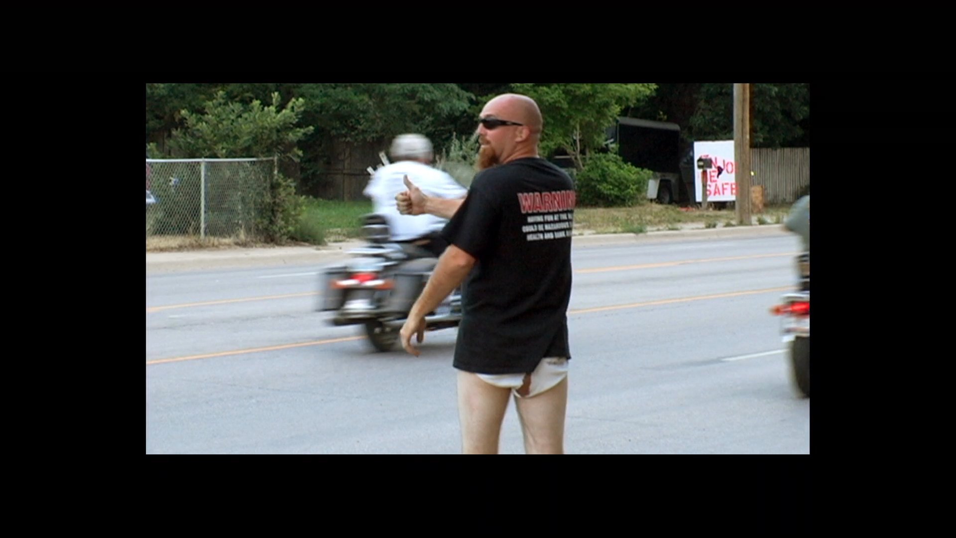 Bikers ride along a scenic highway, interspersed with black screens displaying production credits and cast names.