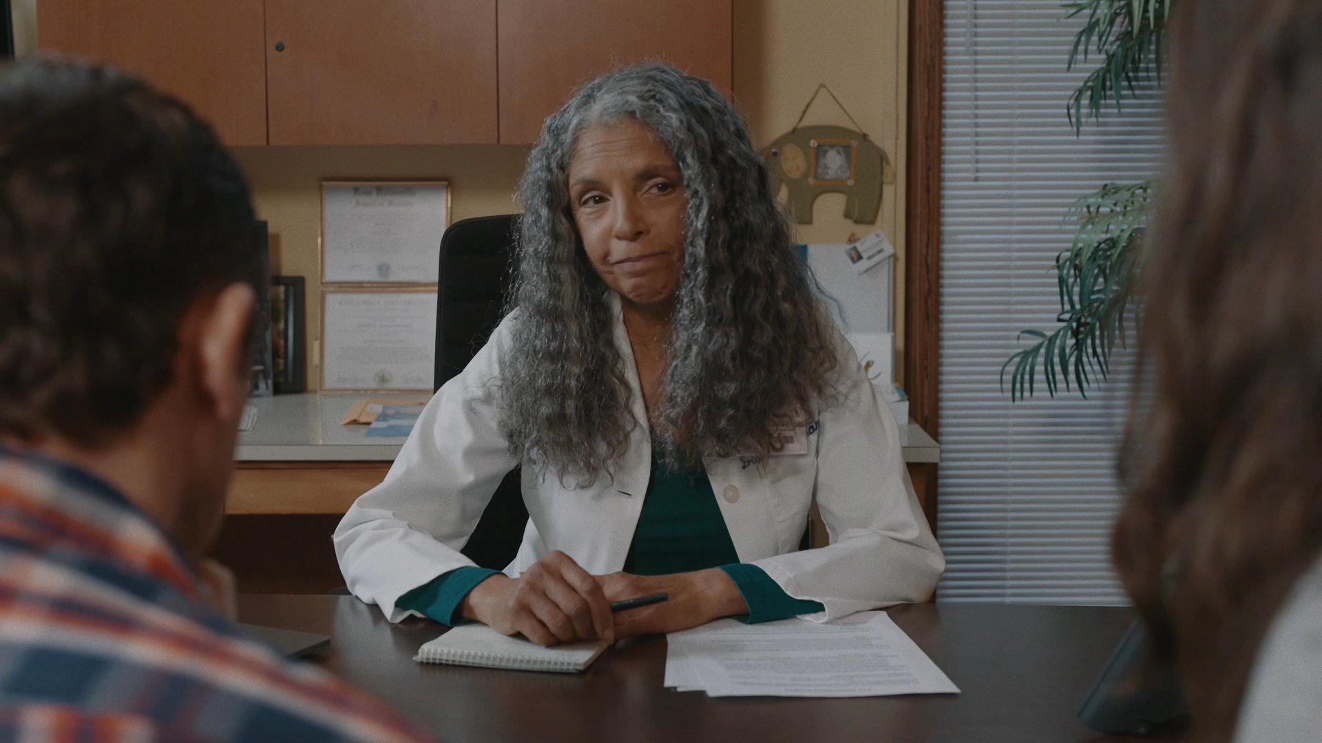 A physician conducts a serious consultation with a couple in an office, discussing medical information and providing professional guidance.