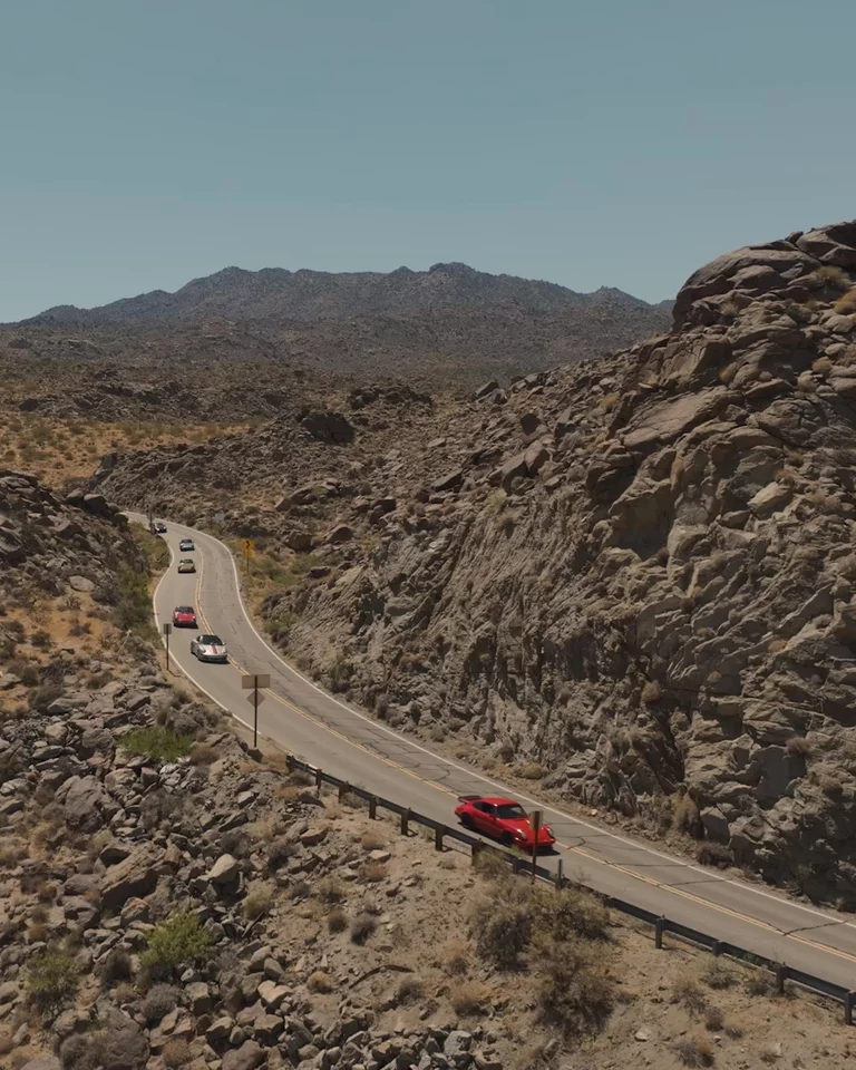 Drone footage of vintage cars driving in Joshua Tree desert landscape