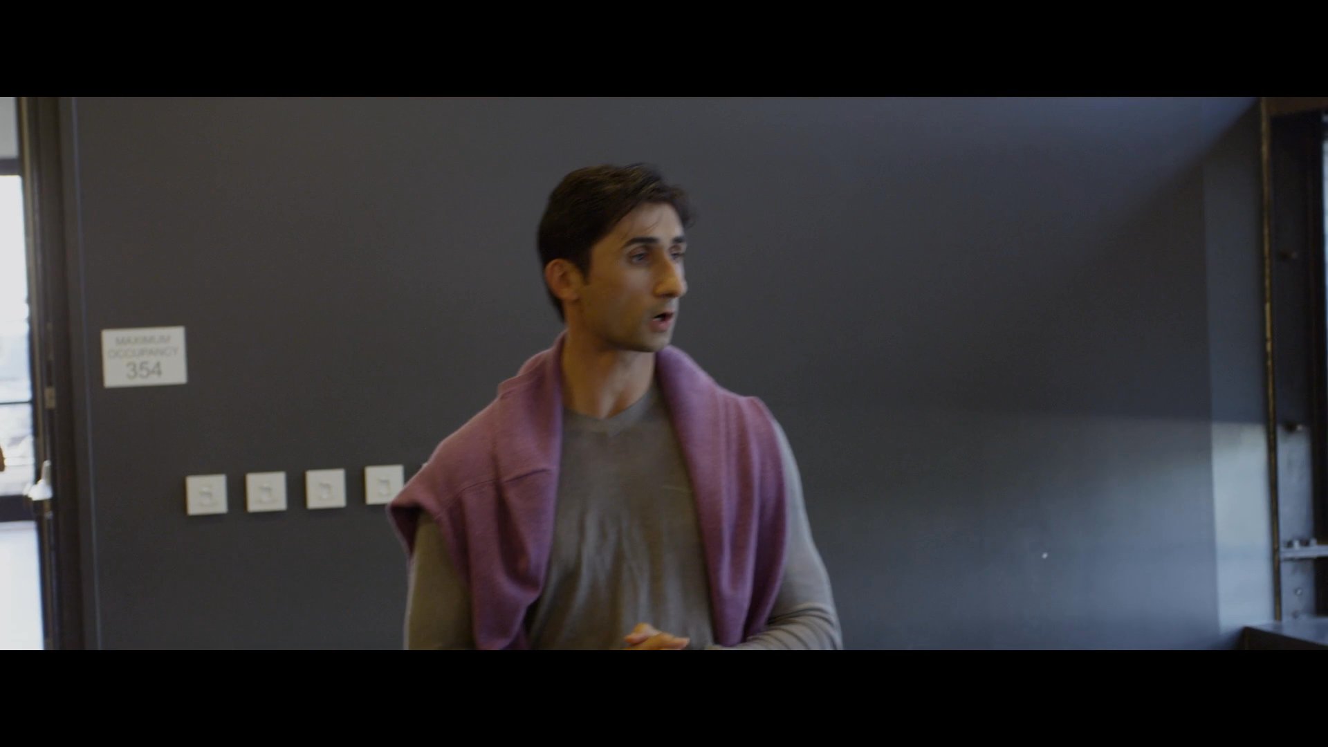 A ballet dancer and an instructor coordinate during a rehearsal session in a professional studio setting. The pair reviews progress and makes adjustments to prepare for a performance.