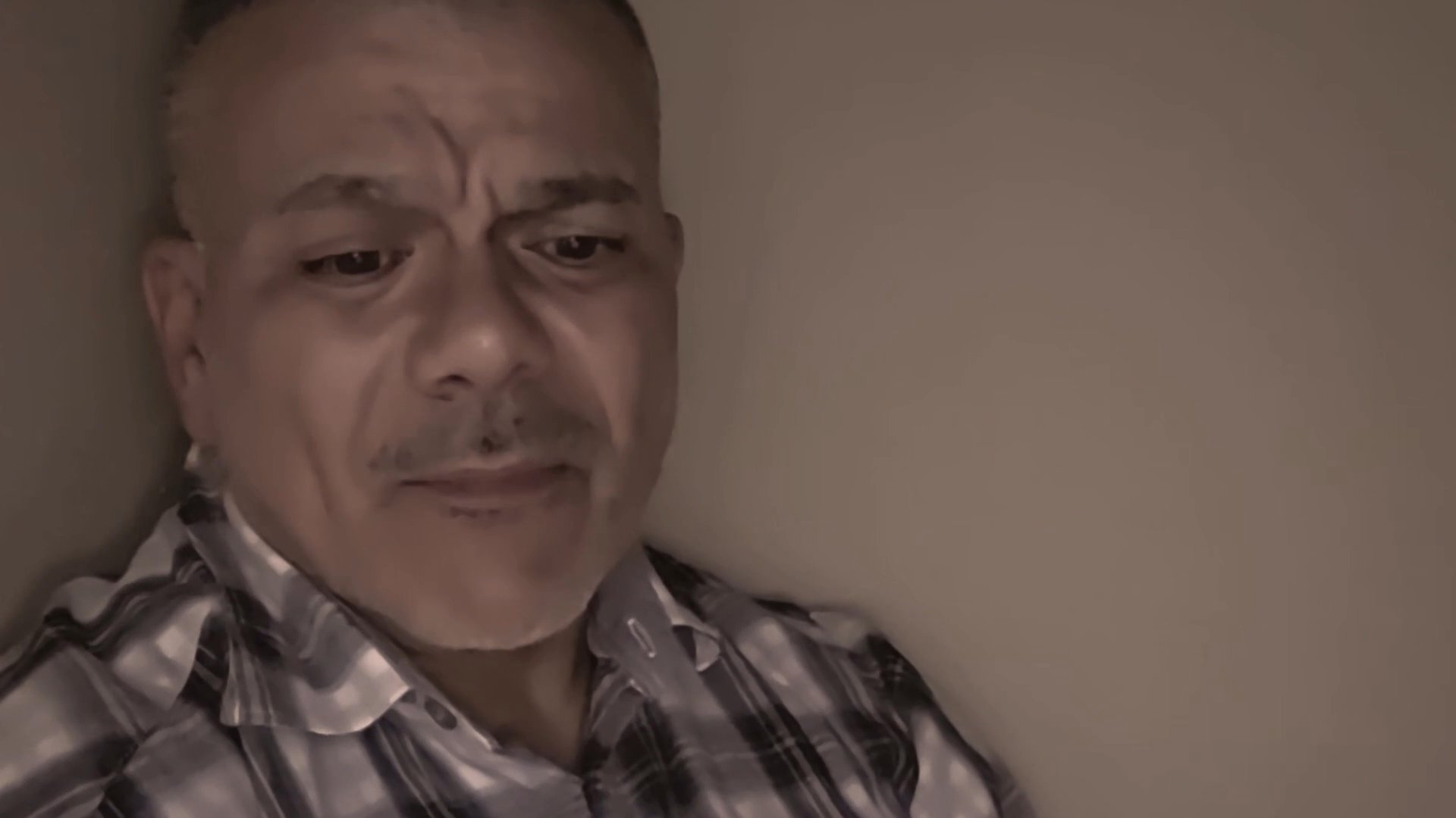 A man speaks directly to the camera, engaging in a focused and expressive monologue in an indoor setting.