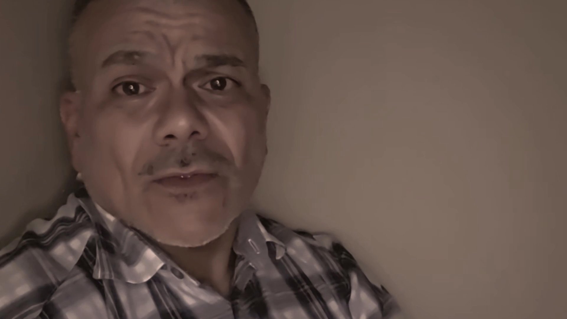 A man speaks directly to the camera, using expressive hand gestures and facial expressions to convey a thoughtful and emotionally resonant message.