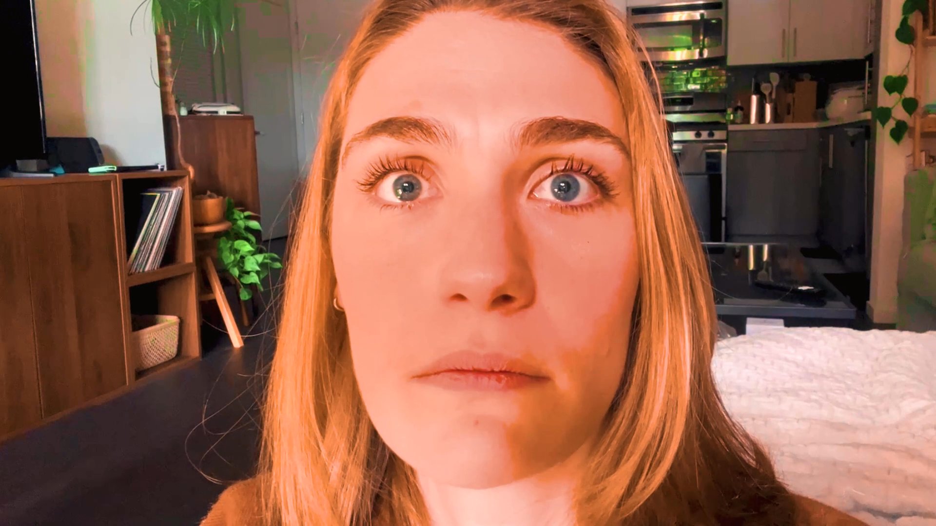 A woman observes a family portrait with a visibly emotional reaction, shifting from confusion to solemn reflection. The visual transition connects her personal expression to the contents of the framed photograph.