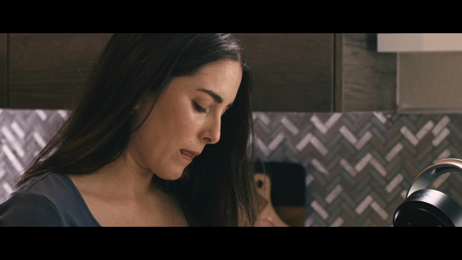A woman speaks directly to the camera within a modern kitchen setting, followed by a wide-angle aerial view of an urban cityscape.