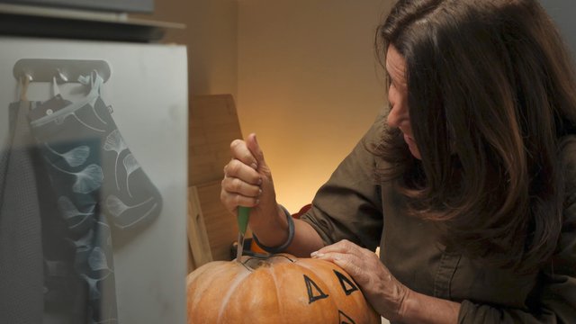 Happy woman carving a pumpkin