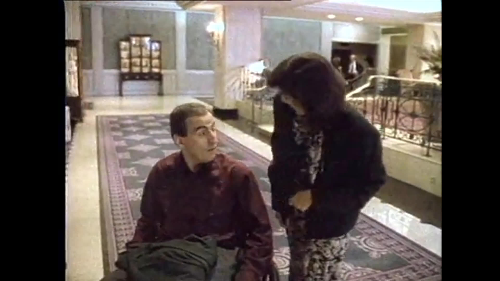A narrator discusses accessibility features while scenes depict a person in a wheelchair navigating a hotel lobby with assistance.