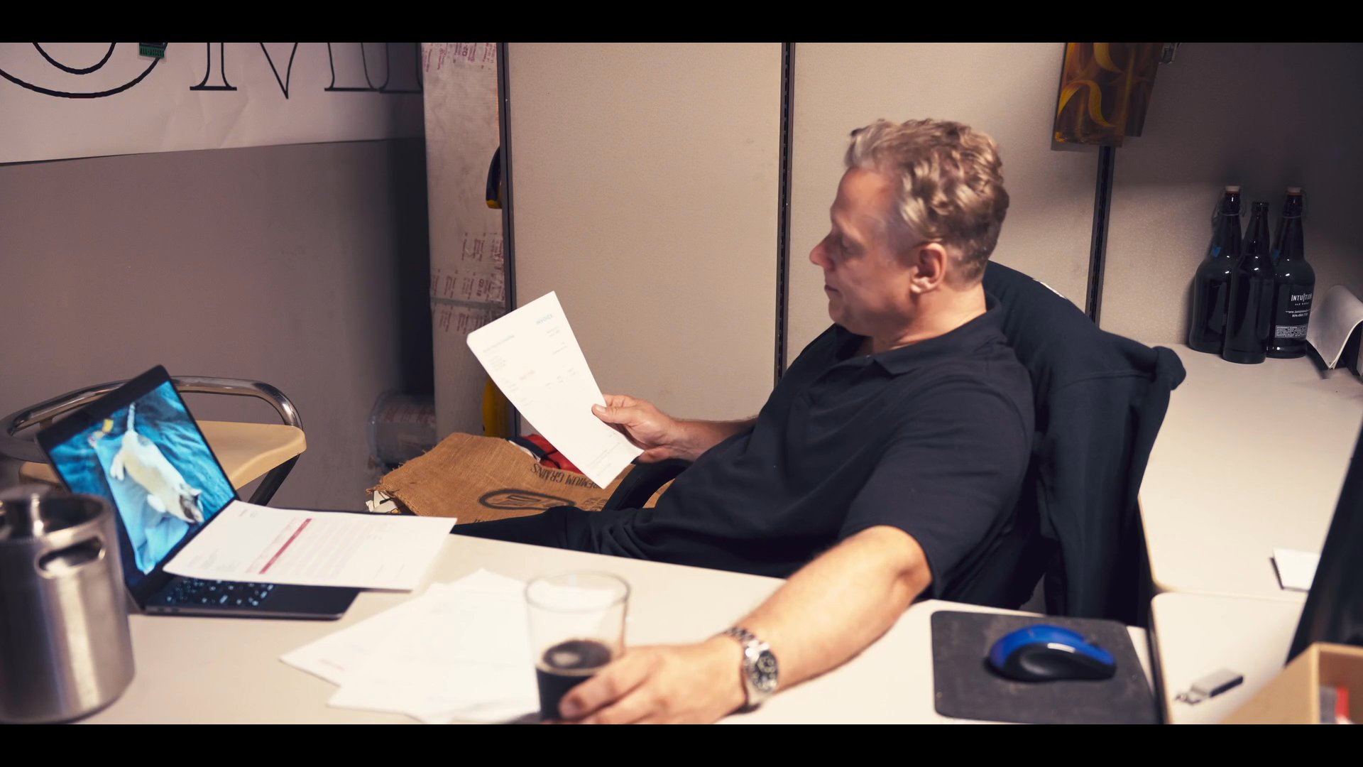 A business professional reviews documents at a desk in an office before a pickup truck traverses an urban landscape. The scene transitions between administrative tasks and exterior street views.