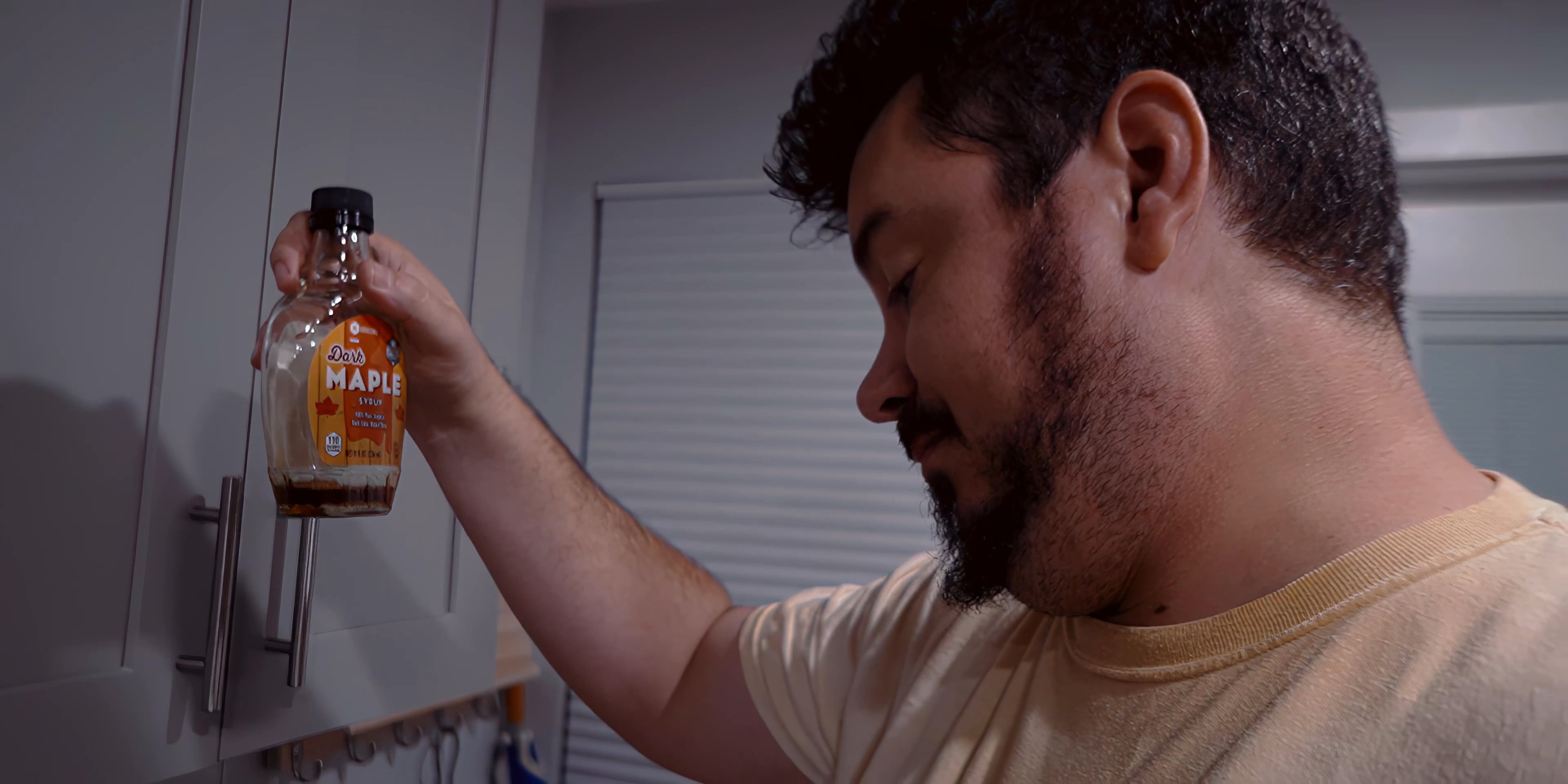A man completes his morning grooming routine before preparing a meal of waffles with maple syrup in his kitchen.