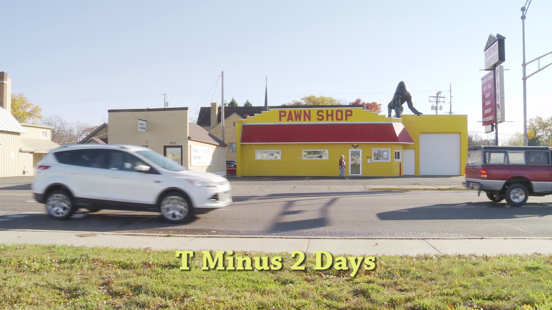 A woman appears visibly distressed while speaking on the telephone inside a home, before the scene transitions to a yellow pawn shop building featuring a large gorilla statue on the roof during a two-day countdown.
